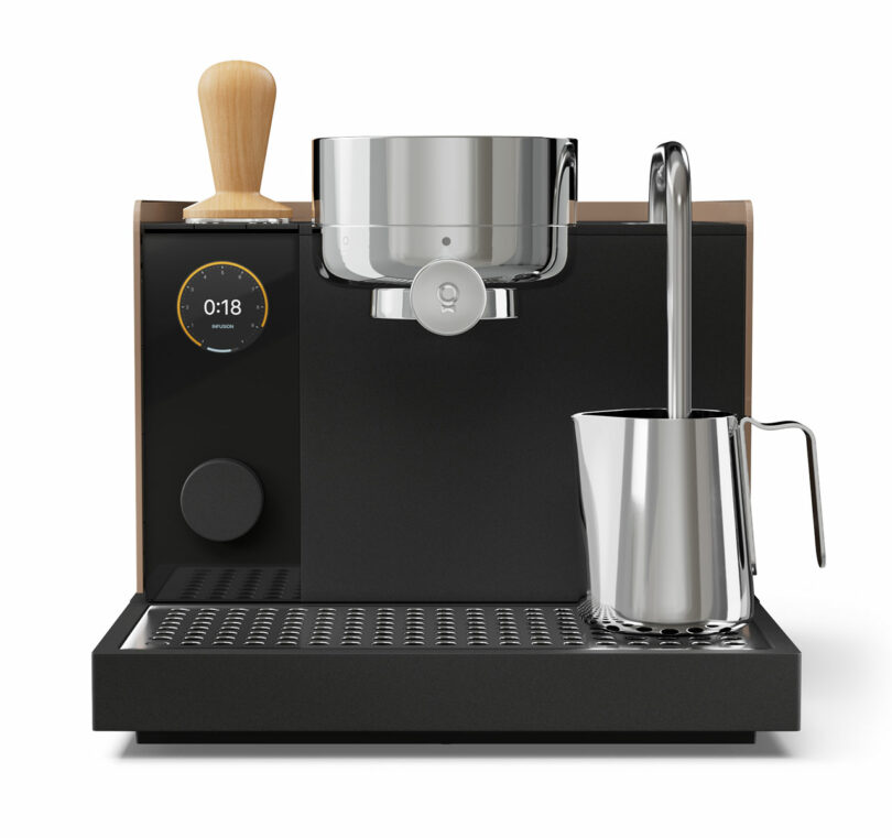 A modern espresso machine with a digital timer, a metal portafilter, and a Fellow stainless steel milk frothing pitcher on the drip tray.