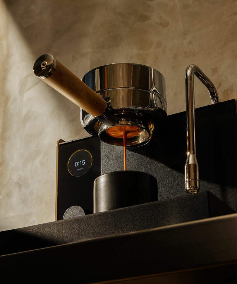 Espresso machine dispensing coffee into a black Fellow cup, with a digital timer showing 15 seconds on the side.
