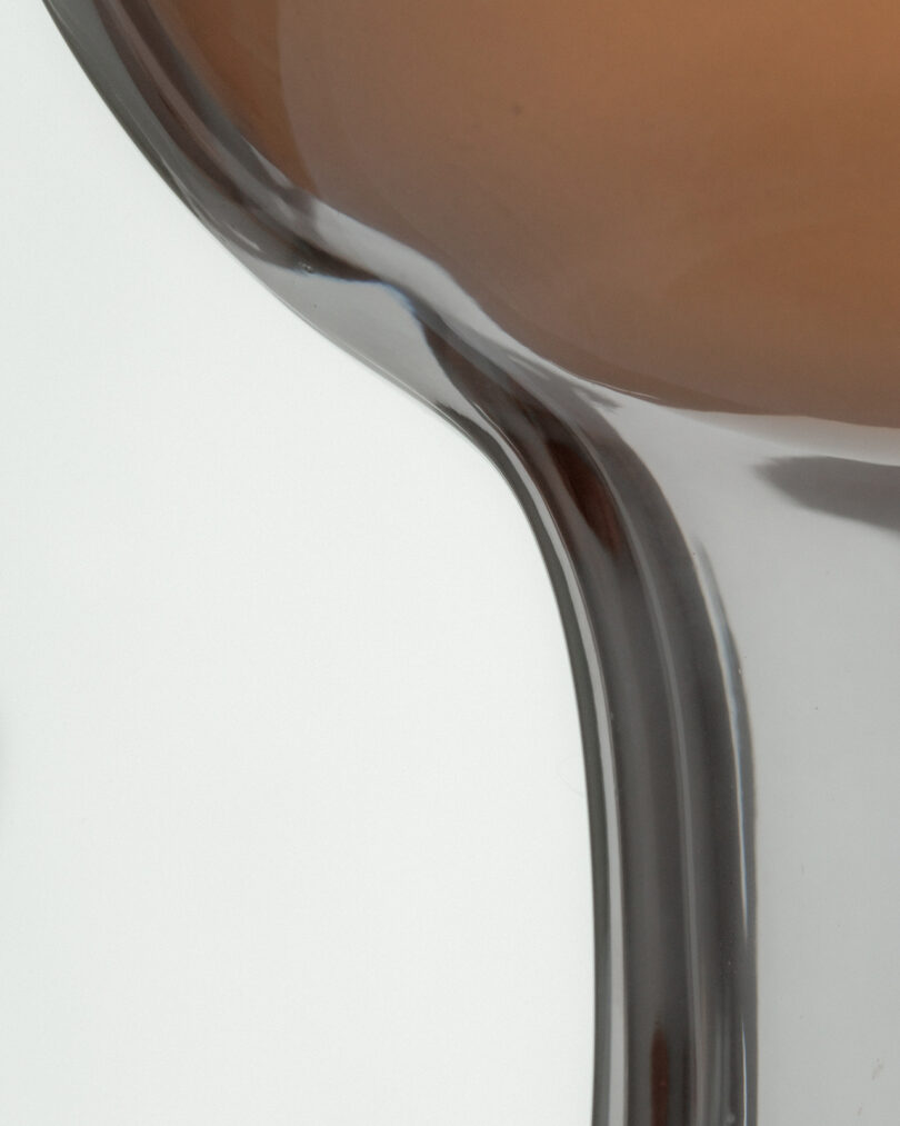Close-up of sand flowing through the narrow center of an hourglass against a plain background.