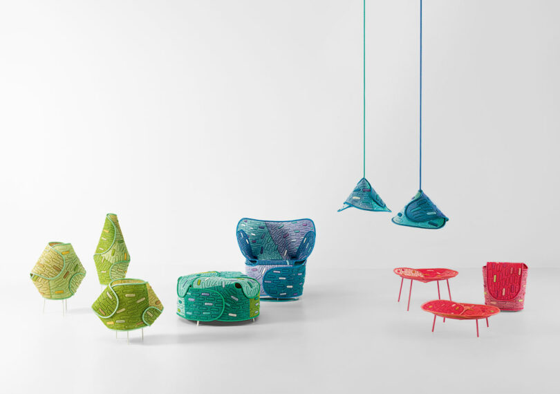 A collection of modern, colorful furniture pieces including chairs, tables, stools, and hanging lamps against a plain white background.