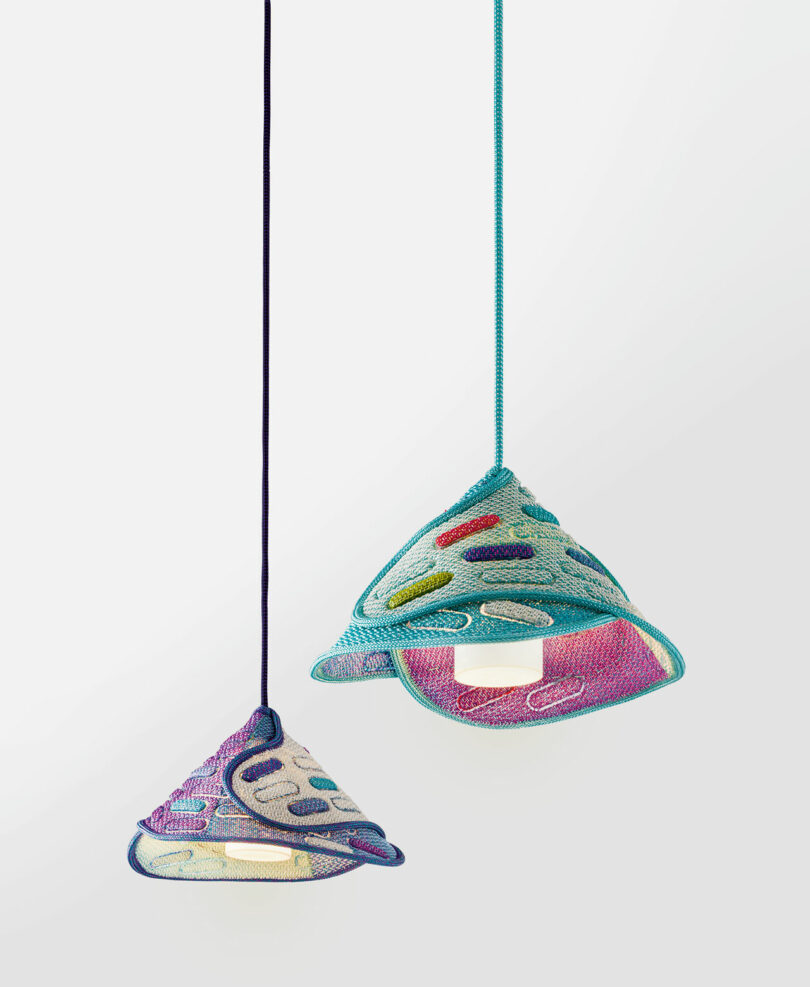 Two pendant lights with conical, open-weave fabric shades in multicolored patterns hang against a plain light background.
