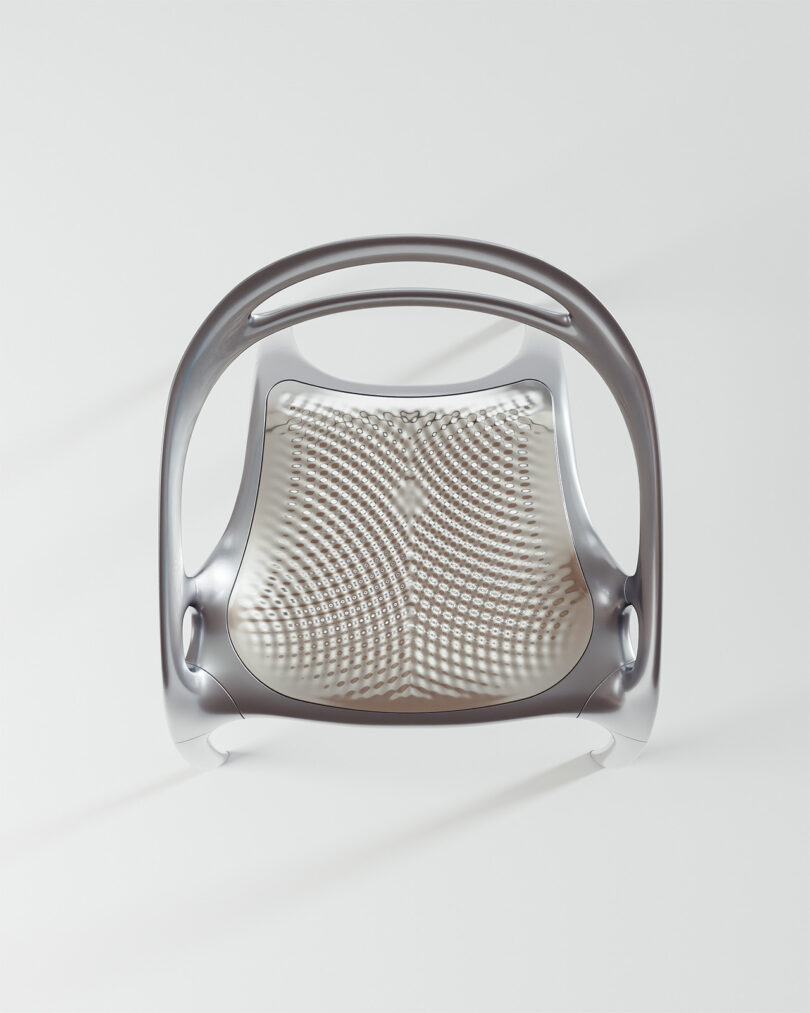 Futuristic metallic chair with a perforated seat and a sleek, curved backrest design.