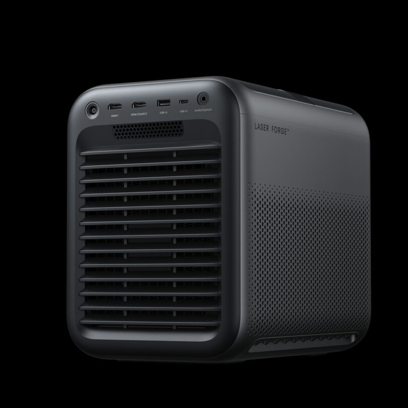 A matte black, box-shaped electronic device labeled "LASER FORGE" features multiple front ports and ventilation grilles against a black background.