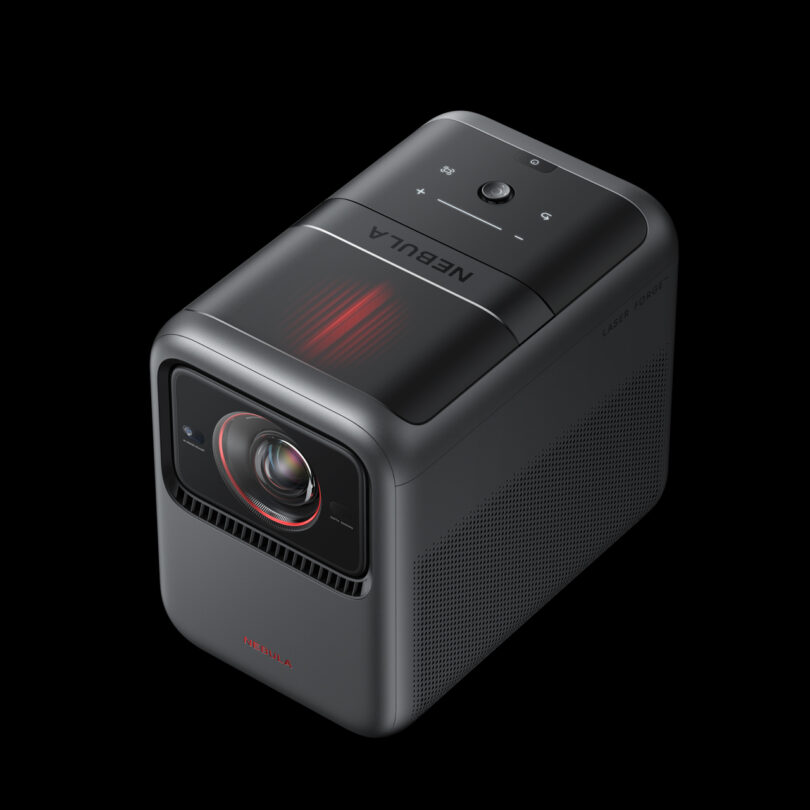 A compact, black Nebula projector with a control panel on top and a lens on the front, shown on a black background.