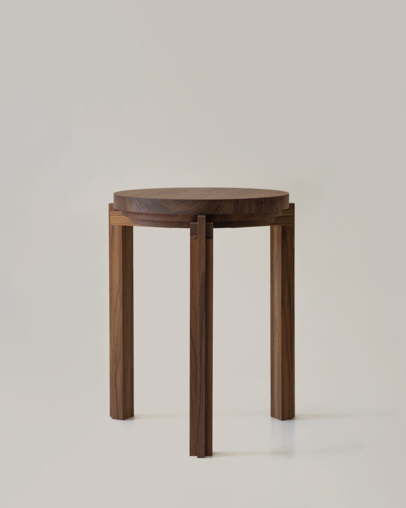 A round wooden stool with three legs set against a plain light background