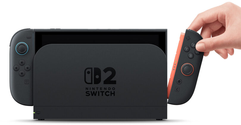 A hand inserts a right Joy-Con controller into a Nintendo Switch console dock labeled "Nintendo Switch 2.