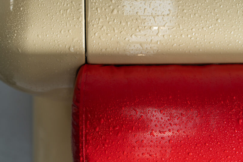 Close-up of a beige and red surface, covered in water droplets, with distinct textures visible