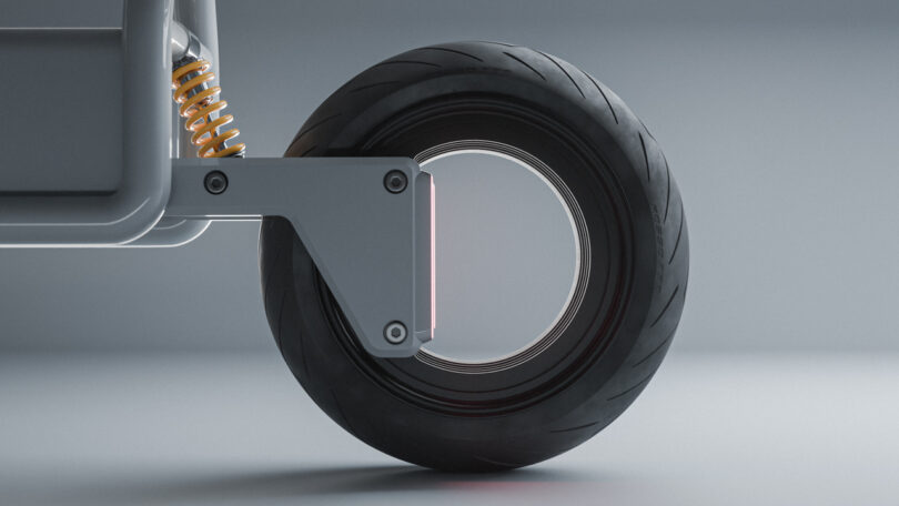 Close-up of a modern, hubless wheel with a thick black tire, mounted on a metallic frame with a visible coil spring suspension.