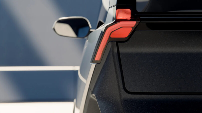 Close-up of the rear left corner of a black vehicle, showing a red LED taillight and side mirror, with sunlight creating shadows in the background.