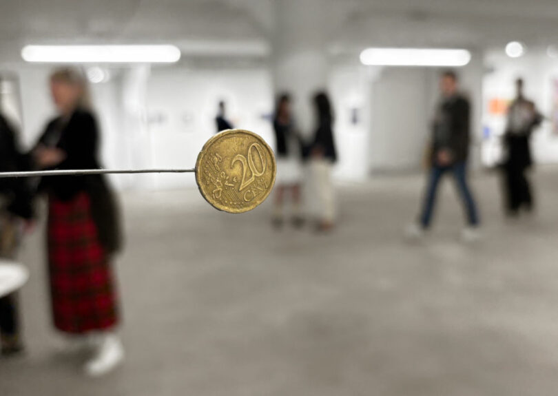 Detail of coin hanging in art fair crowd