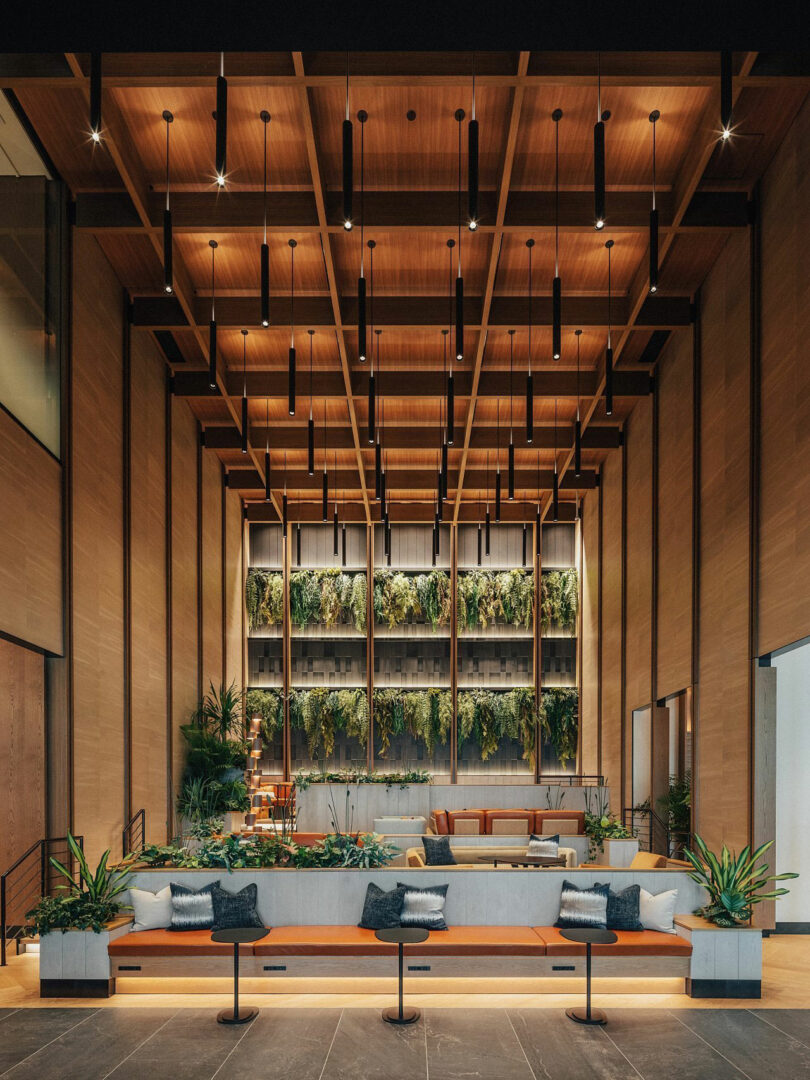 Modern lobby with wooden ceiling, a vertical garden wall, contemporary chairs and soft lighting, with plants and pillows with neutral tones inspired by the innovative ethos of Jun Aizaki's design design.