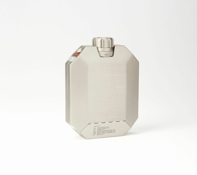 Metallic rectangular container with a screw cap, placed upright on a plain white background, reminiscent of the minimalist style favored by Neil Ferrier.