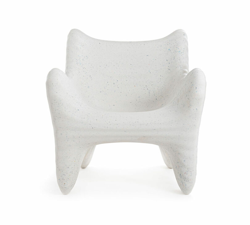 A white, modern armchair with a sculptural, rounded form and four wide, tapered legs—reminiscent of the In-Side Thomas Heatherwick aesthetic—viewed from the front.