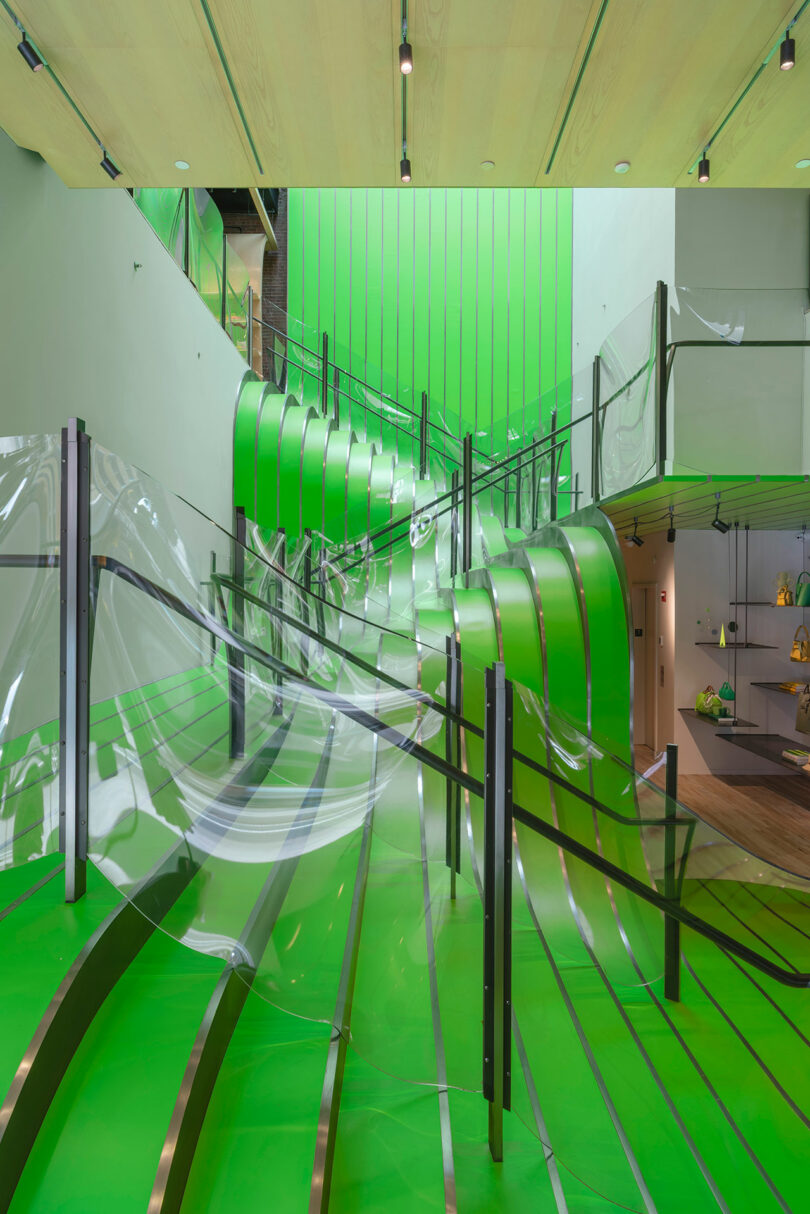 Modern interior with bright green walls and floors, featuring a curved staircase and transparent panels, creating a futuristic and open atmosphere.