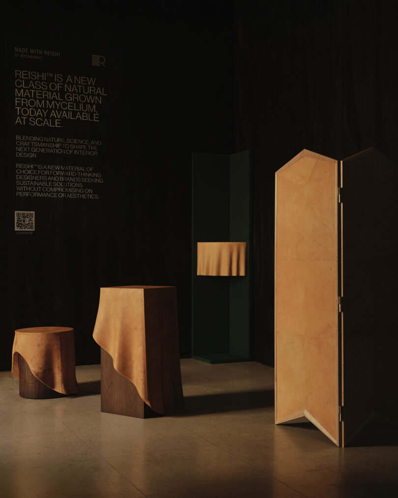 A dark room displays contemporary furniture and a screen, each draped with tan-colored material, promoting a new natural product grown from mycelium.