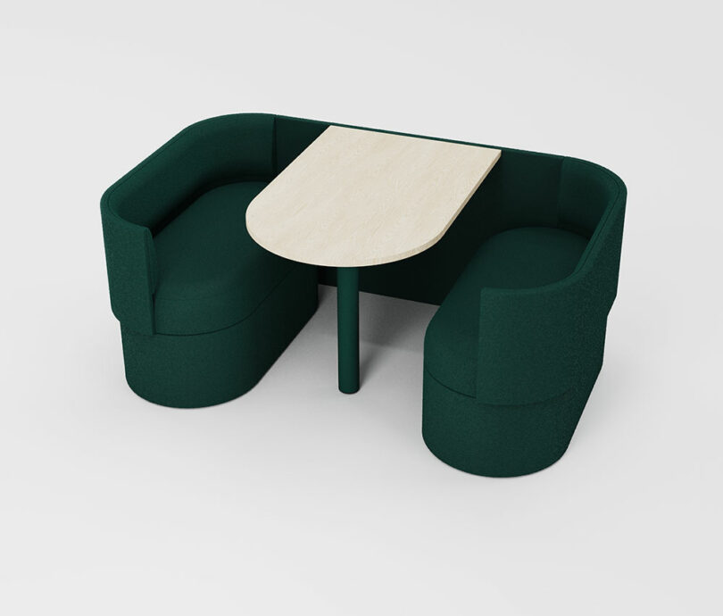 Two dark green upholstered benches facing each other with a light wood oval table between them, set against a plain white background.