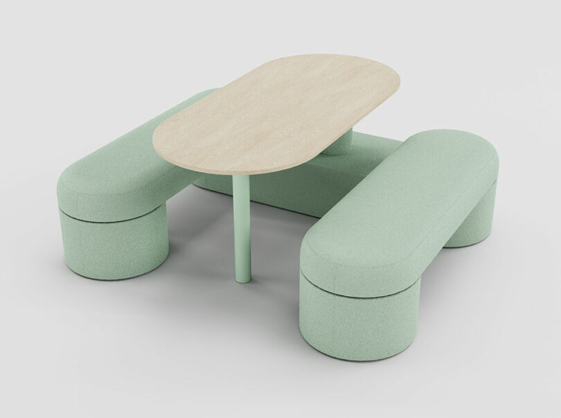 A modern seating arrangement with two curved, mint-green upholstered benches and a light wood oval table on a matching mint-green leg.