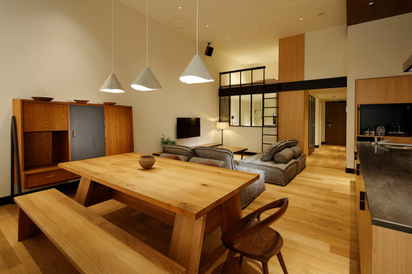 The modern living and dining area with wooden furniture and gray sofas, pendant lights and minimalist decor