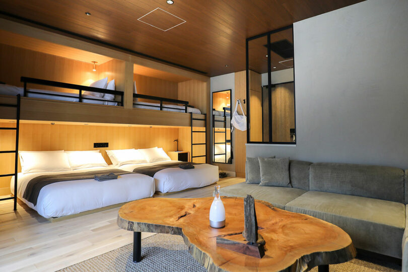 Modern trunk room (hotel) with two double beds, two bunk beds, a large green section and a wooden coffee table with minimalist decor