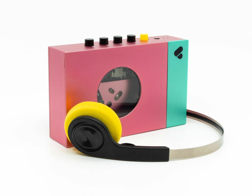 The WE-001 Edith is a retro-style cassette player in pink and teal, featuring control knobs on top, a visible cassette through a window, and yellow-cushioned black headphones.