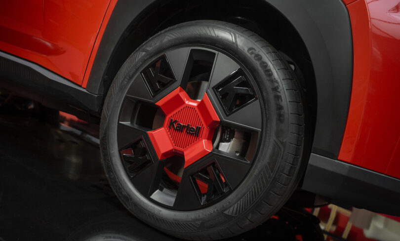Close-up of a red and black car wheel with a Goodyear tire and the word "Kartell" on the center cap