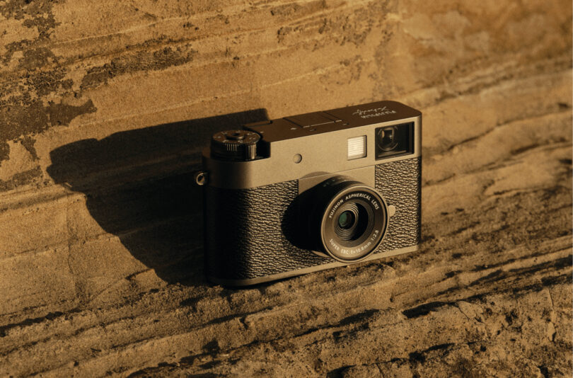 A black camera with a textured grip is placed on a sunlit, textured stone surface.