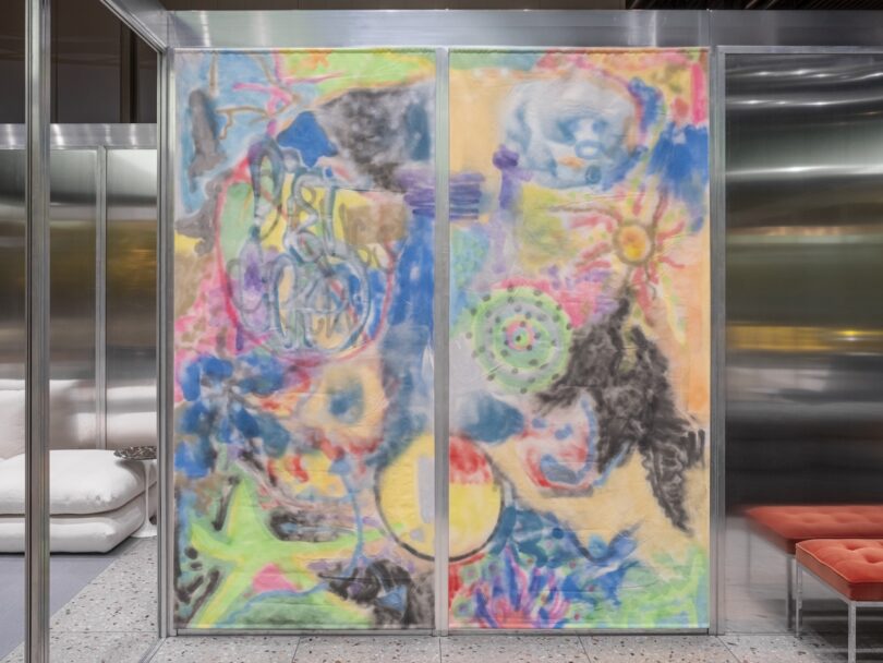 A large abstract painting with colorful, swirling shapes and varied textures is displayed within a metal-framed glass partition in a modern interior setting