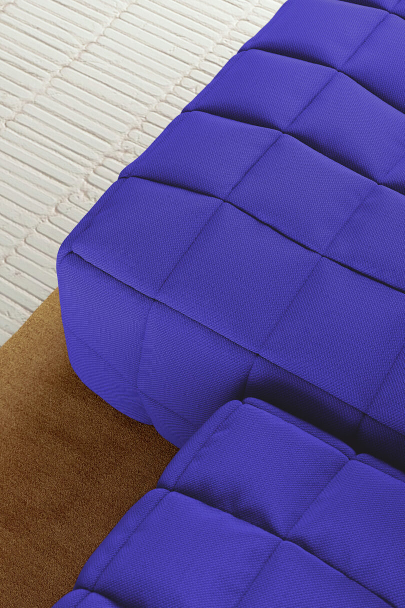 Close-up of blue, quilted seat cushions on a textured brown surface, with a white tile floor in the background