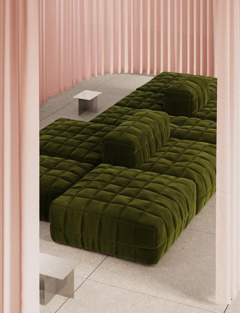 Olive green modular sofa set on a light-colored tiled floor, surrounded by pink floor-to-ceiling curtains and two low, rectangular tables