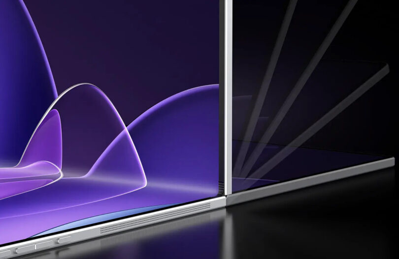 A close-up of a sleek, modern laptop with a partially open transparent display and a purple abstract background on the screen.