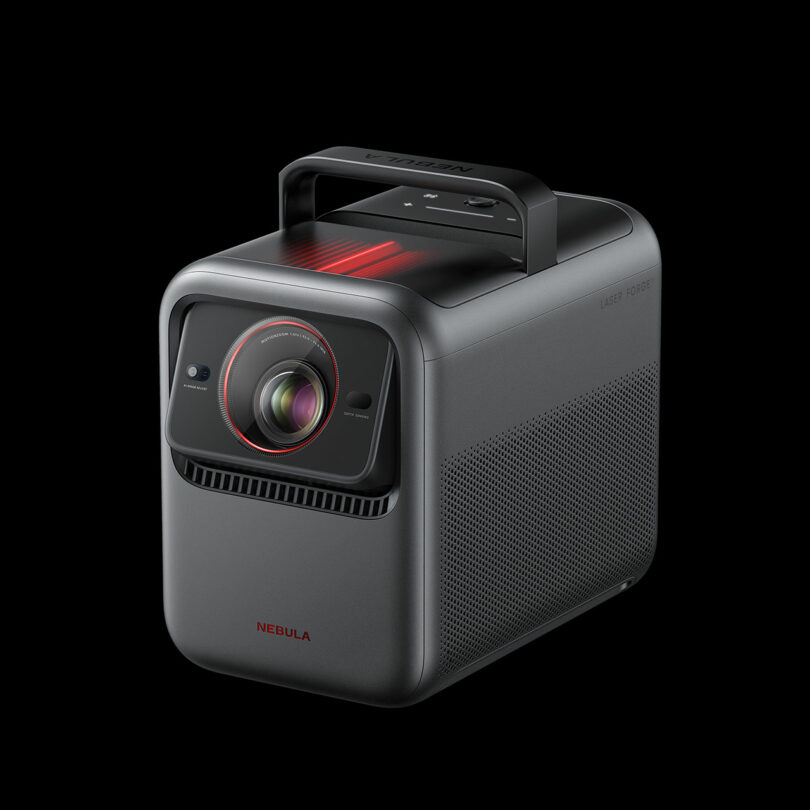 The Nebula X1 is a black portable projector featuring a sturdy handle on top, a prominent lens on the front, and the brand name “Nebula” displayed at the bottom front.