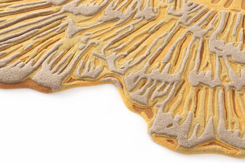 Botanica Bodo Sperlein textured rug in shades of gold and beige features raised, organic patterns resembling fungal gills or natural formations, displayed on a white background.