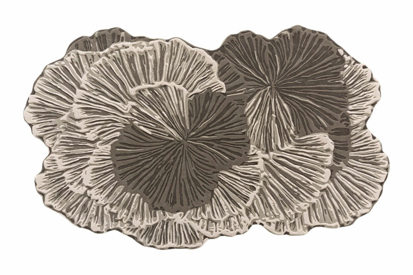A textured rug inspired by Botanica Bodo Sperlein, featuring a design resembling overlapping mushroom caps in soothing shades of beige, taupe, and brown.