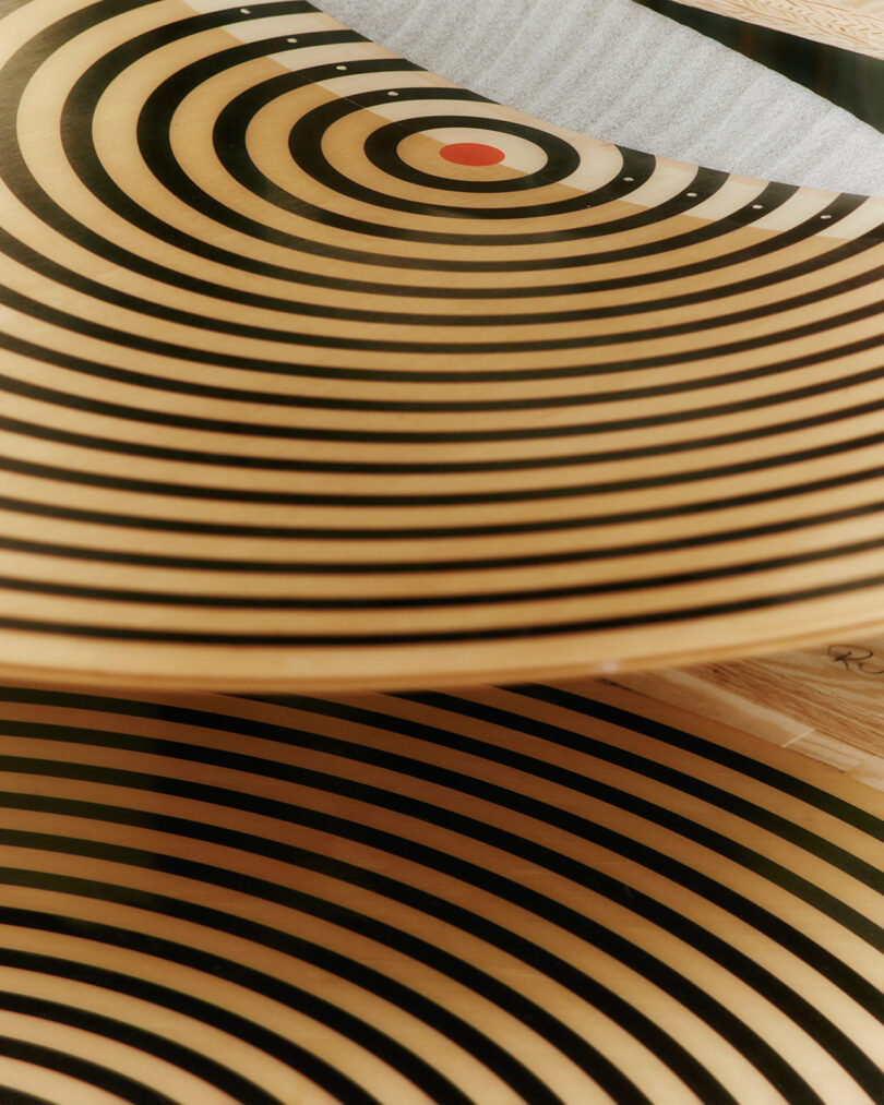 Close-up of wooden surfaces with black concentric circles and a red dot at the center, resembling a target pattern.