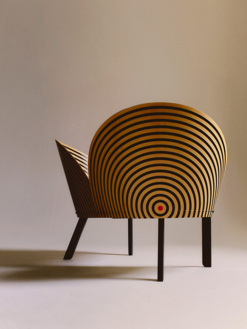 A chair with a rounded back and concentric black and yellow circles, finished with black legs, set against a neutral background.