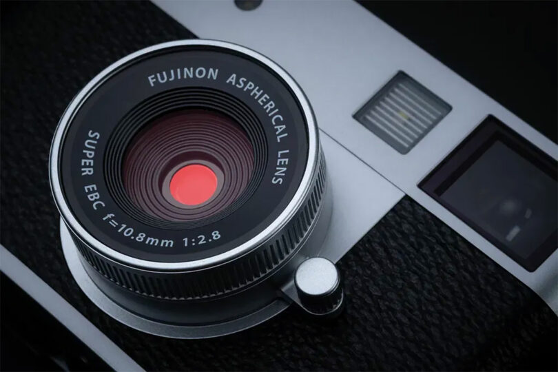 Close-up of a Fujinon aspherical lens on a Fujifilm camera, showing detailed text around the lens and part of the camera body.