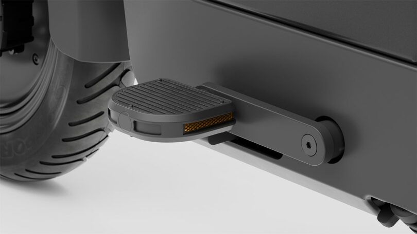 A close-up of a foldable rear step attached to a vehicle near the wheel, shown in the extended position.