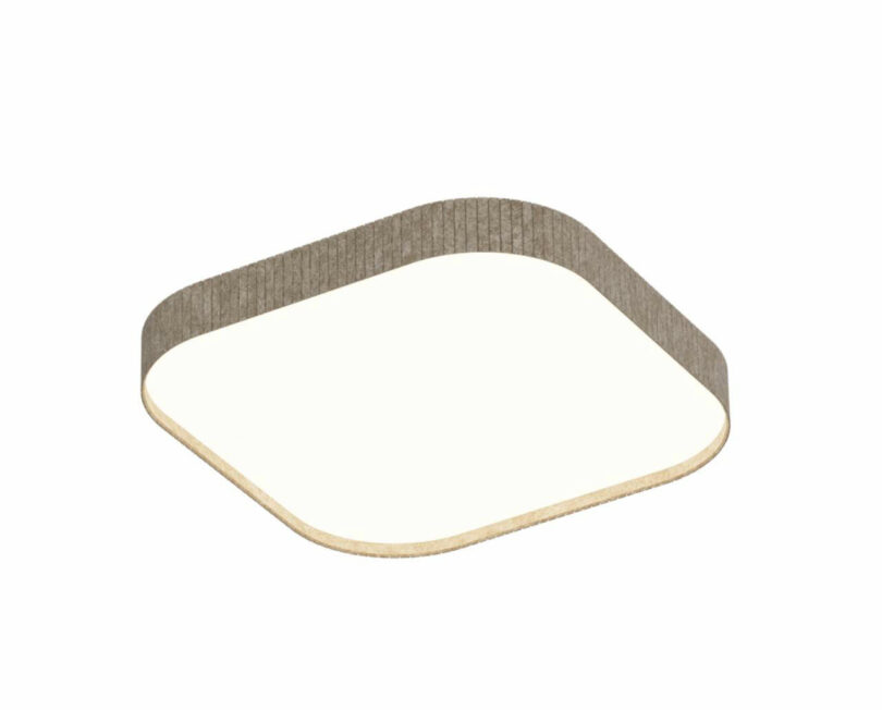 A square sheet of light-colored material with rounded corners, bordered by a thin, upright, textured strip.
