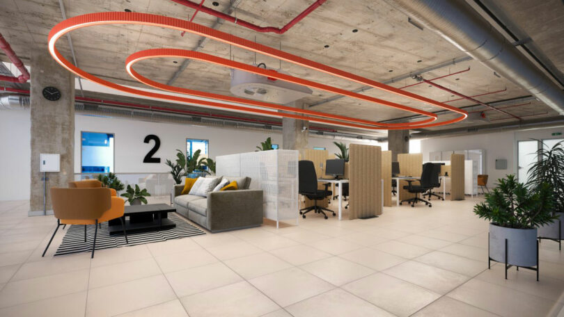 Modern open-plan office with exposed ceilings, orange accent lighting, partitions, greenery, a sofa, armchairs, desks, and a large number 2 on the wall.