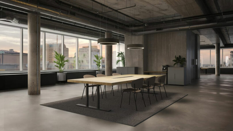 A modern conference room with a large wooden table, six chairs, potted plants, circular ceiling lights, and large windows overlooking city buildings.