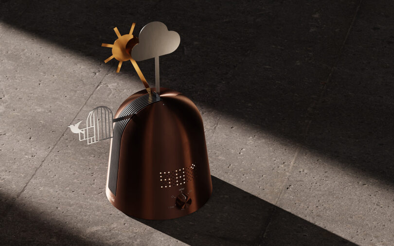 A small metallic object with sun, cloud, and birdcage decorations casts a shadow on a textured stone surface.