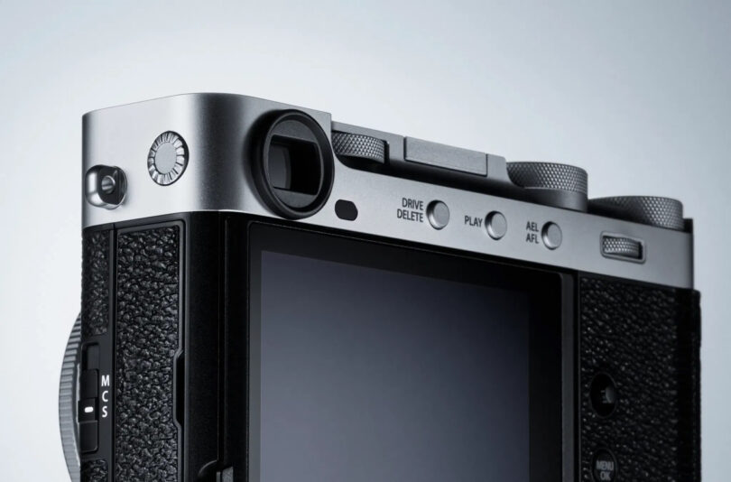 Close-up of the top rear corner of a Fujifilm X-E5 digital camera, showing buttons, dials, a textured grip, and the edge of the LCD screen.