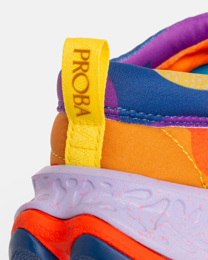 Close-up of a colorful sneaker heel featuring a yellow pull tab with the word “PROBA” and a textured, multicolored sole