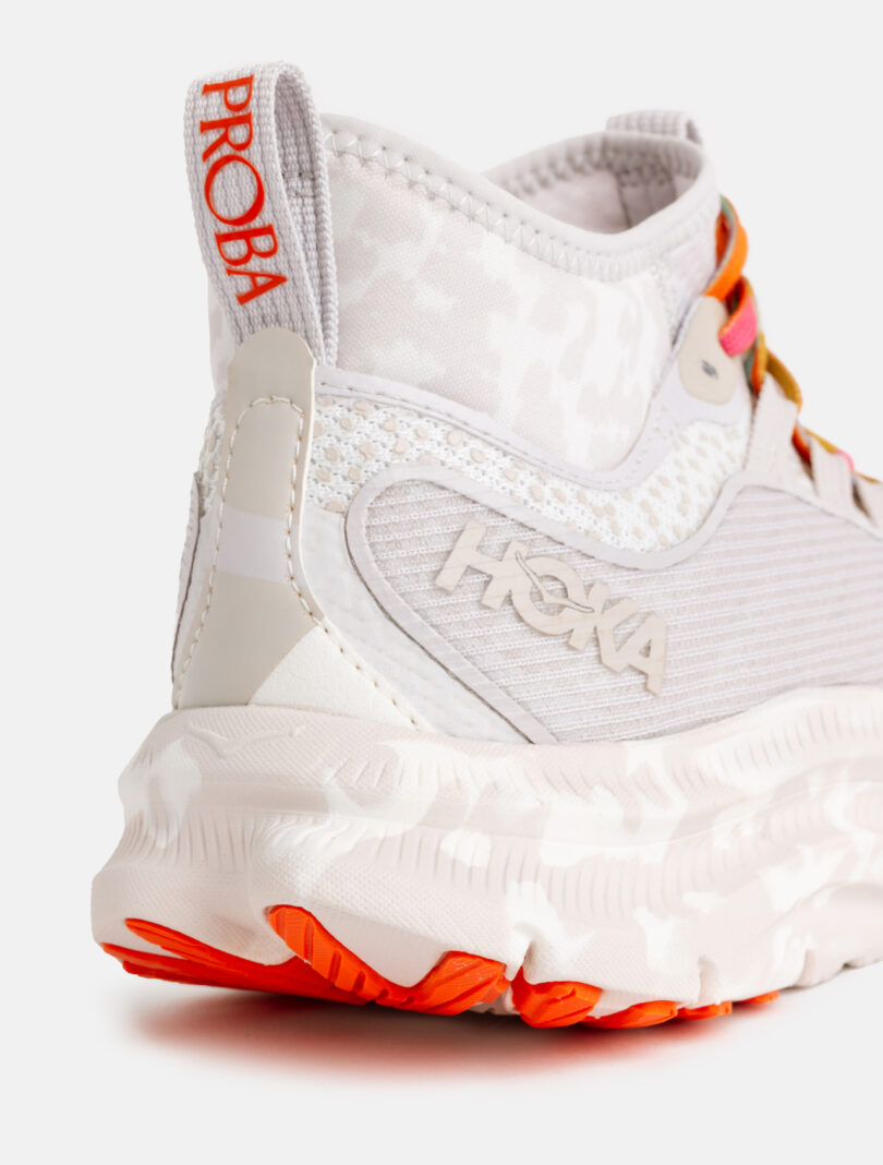 Close-up of the heel and side of a white Hoka running shoe with red-orange accents, textured sole, and "PROBA" and "HOKA" branding visible