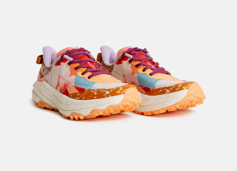 A pair of multicolored athletic sneakers with orange soles, purple and pink laces, and a patterned upper, displayed on a white background