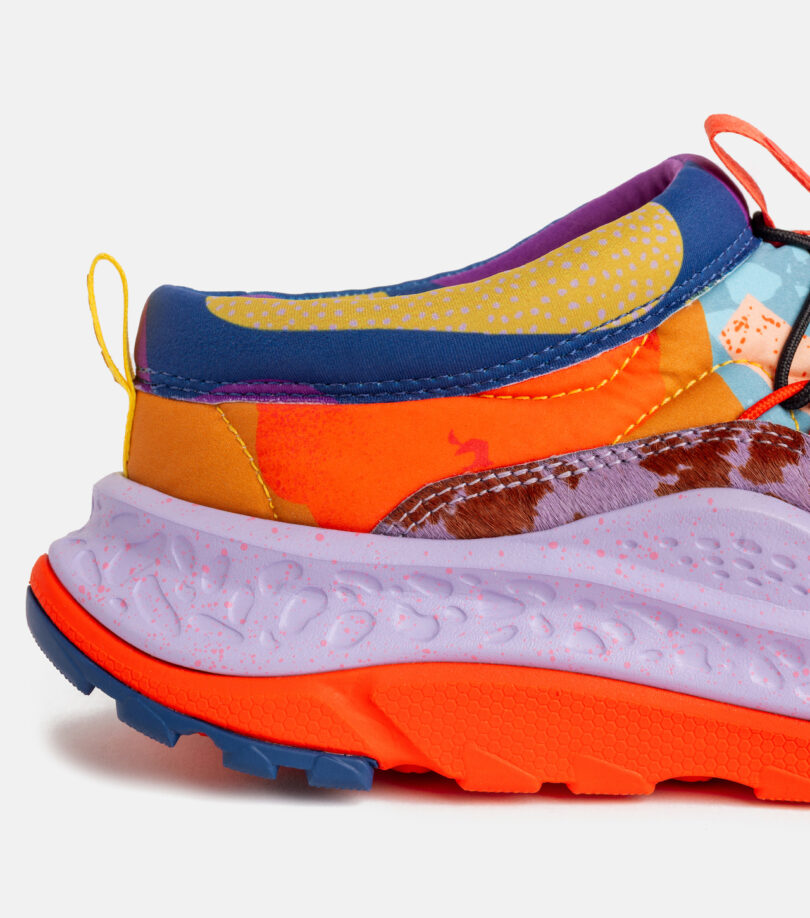 Close-up of the heel and sole of a colorful, patterned sneaker with shades of orange, purple, blue, and yellow on a plain white background