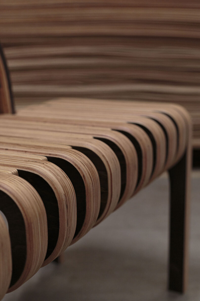 Close-up of a modern chair made from curved, layered wooden slats with a smooth, minimalist design