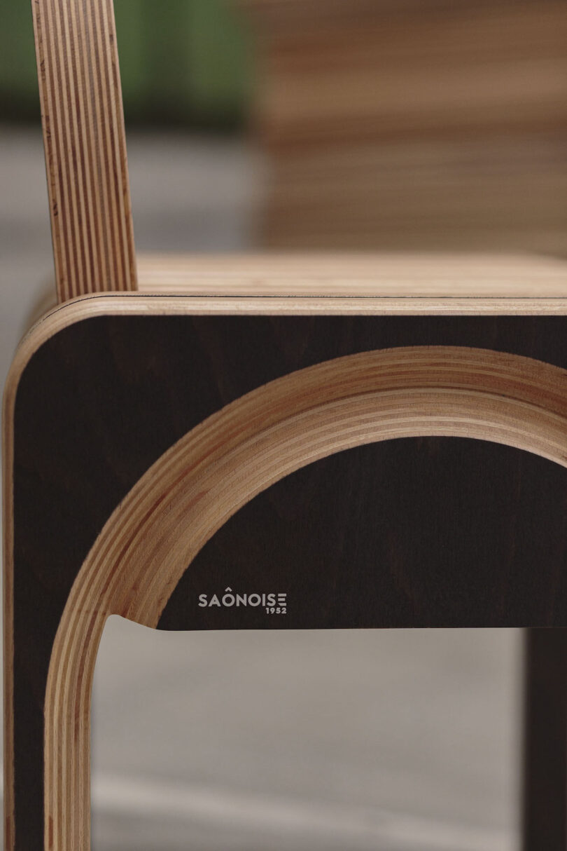 Close-up of a modern wooden chair with layered plywood construction and the brand name “SAÔNOISE 1953” visible on the side