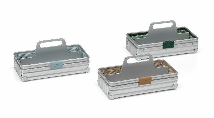 Three rectangular metal caddies with handles in silver, each featuring a different colored label and mesh liner: blue, green, and tan—bringing a touch of Vitra Rimowa-inspired style to your organization.