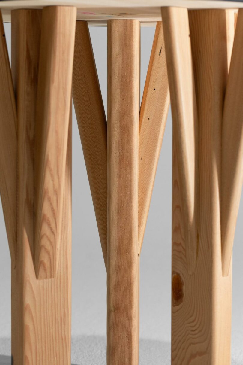 Close-up view of a wooden table base with multiple legs arranged in a geometric pattern, showcasing the natural wood grain and texture